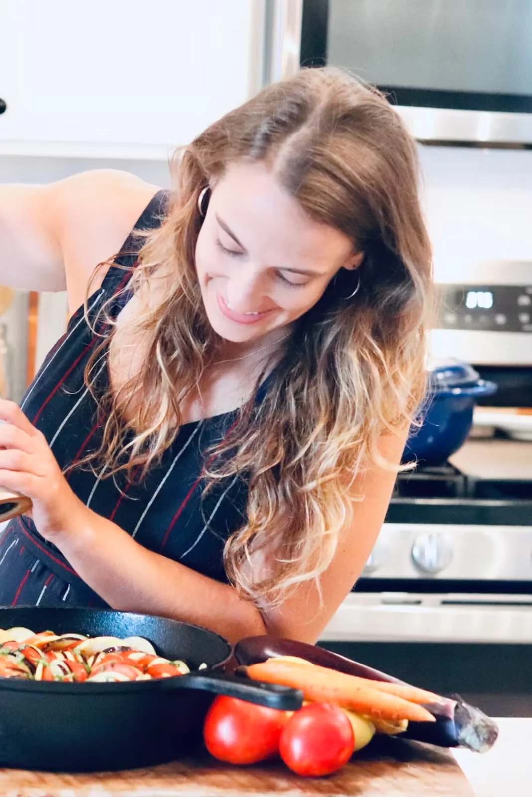 Allie Redding preparing a colorful vegetable dish in her kitchen