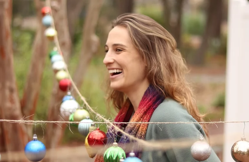 Allie laughing outside under warm string lights
