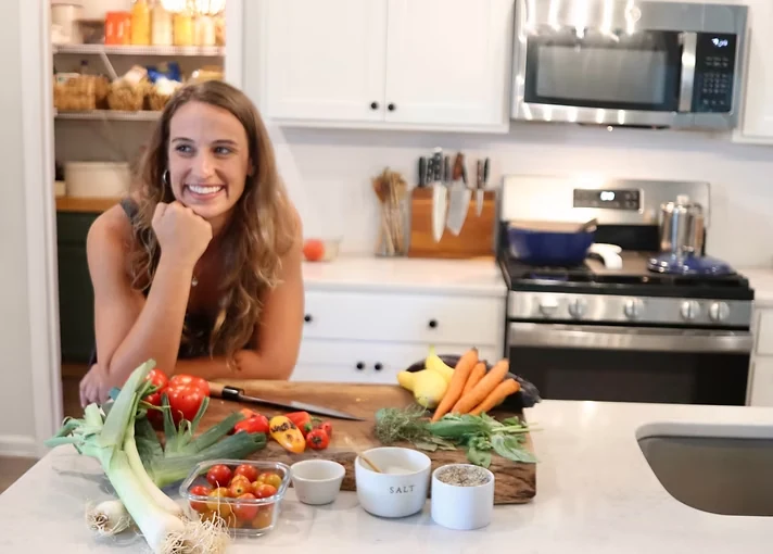 Allie in her kitchen with an assortment of fresh vegetables
