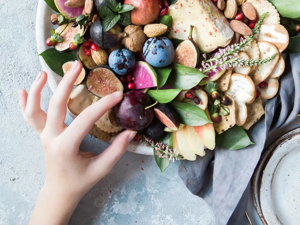 An overhead grazing board with fruit, vegetables, cheese, bread, nuts, and dips