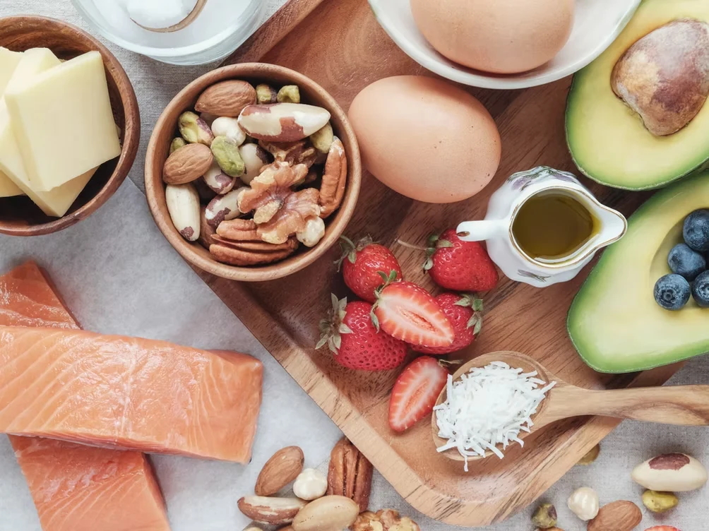 A colorful balanced spread with salmon, eggs, avocado, fruit, nuts, and vegetables
