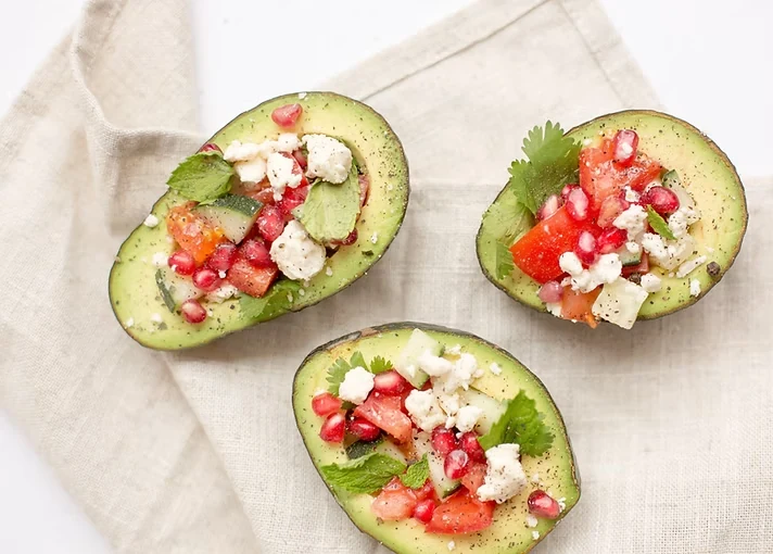 Stuffed avocado with tomatoes, feta, herbs, and pomegranate