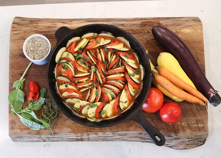 A colorful skillet of sliced summer vegetables and fresh herbs