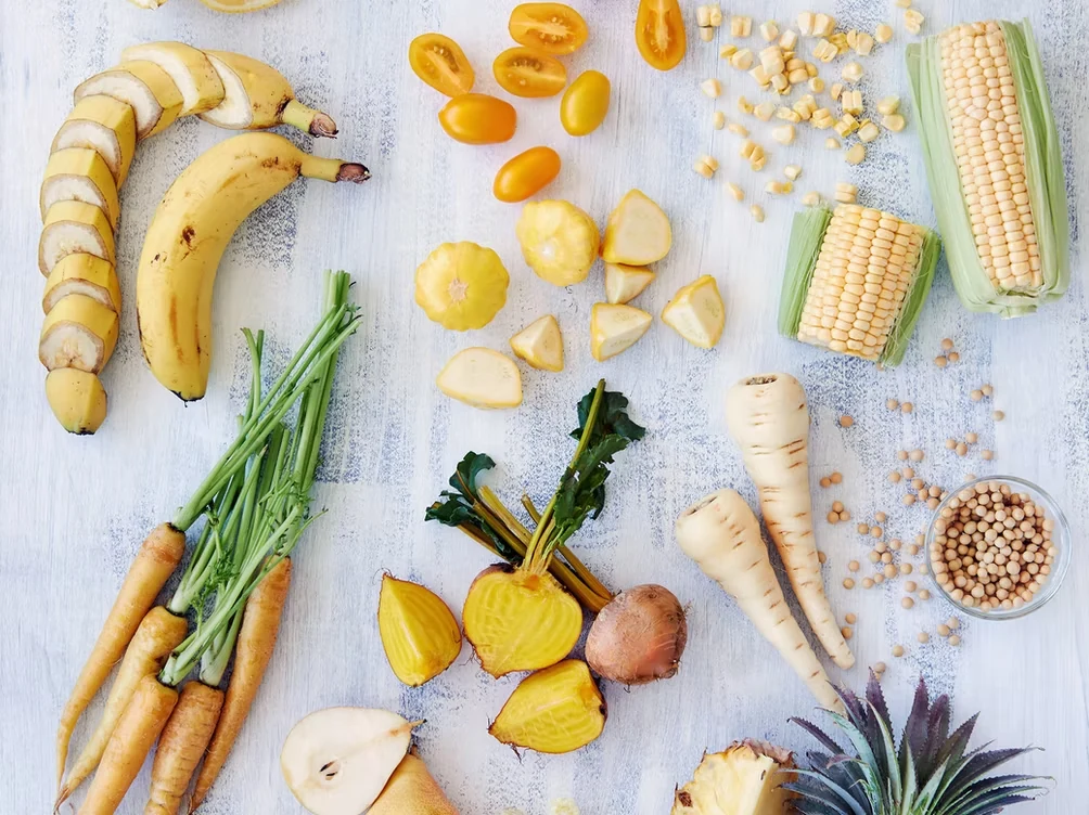A bright assortment of bananas, corn, carrots, parsnips, and chickpeas